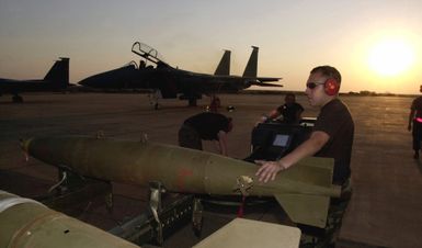 At Air Force Base (AFB) Louis Trichardt, South Africa, US Air Force (USAF) SENIOR AIRMAN (SRA) Brian Manibusan, from Guam, assigned to the 48th Fighter Wing (FW), Equipment Maintenance Squadron (EMS) and other members of his unit install conventional munitions onto an F-15 Strike Eagle, for a training mission over a South African Air Force (SAAF) bomb range