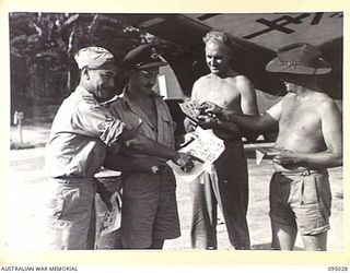 PIVA AIRSTRIP, TOROKINA, BOUGAINVILLE. 1945-08-15. MEMBERS OF THE ROYAL NEW ZEALAND AIR FORCE AND ROYAL AUSTRALIAN AIR FORCE IN HEADQUARTERS 2 CORPS AREA, LOOKING AT SURRENDER LEAFLETS BEFORE ..