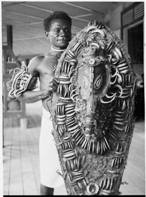 Man holding a large shield decorated with pig tusks, Awar, Sepik River, New Guinea, 1935, 2 / Sarah Chinnery