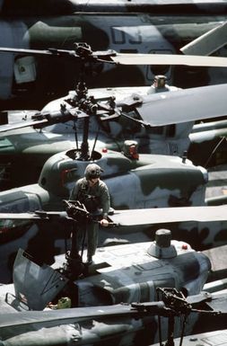 A Marine flight crewman checks the main rotor of a UH-1N Iroquois helicopter on the flight deck of the amphibious assault ship USS SAIPAN (LHA 2) during Operation Sharp Edge. Marines embarked aboard the SAIPAN have been sent to the U.S. Embassy in Monrovia, Liberia, to augment security and evacuate U.S. and foreign nationals from the fighting between government and rebel forces