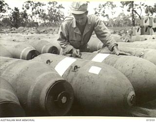 1943-06-25. NEW GUINEA. TECH SERGEANT JOHN D. MILLS OF MONROE, NORTH CAROLINA, CHECKING OVER 1000 AND 2000 POUND BOMBS. THESE BOMBS ARE WAITING TO GO TO LIBERATOR AND FLYING FORTRESS UNITS. ..