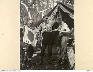 FORTIFICATION POINT, NEW GUINEA, 1944-03-15. MEMBERS OF THE 32ND FIELD SECURITY SECTION, INTELLIGENCE CORPS WITH A CAPTURED JAPANESE FLAG AND A 12 FOOT LENGTH OF JAPANESE FUNDORSI SCARF. IDENTIFIED ..