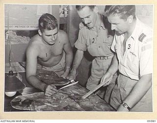 PIVA AIRSTRIP, JACQUINOT BAY, NEW BRITAIN, 1945-07-17. CAPT I.H. BARNES G3 (INTELLIGENCE) AIR LIAISON 5 DIVISION (2), F-LT L.J. SMALL, RNZAF INTELLIGENCE OFFICER (3) AND LAC HEALY (1), WITH PHOTO ..