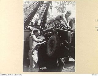 BOUGAINVILLE. 1945-08-30. CRAFTSMAN W.E. GILL (1) AND CRAFTSMAN R. WORMINGTON (2), MEMBERS OF 202 LIGHT AID DETACHMENT ATTACHED HEADQUARTERS 3 DIVISION, USING POWER CRANE ON REAR OF BREAKDOWN TRUCK ..