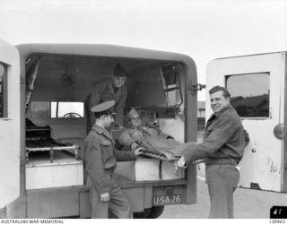 MELBOURNE, VIC. 1943-08-15. OSMAR WHITE, MELBOURNE "SUN" NEWSPAPER WAR CORRESPONDENT WITH THE UNITED STATES FORCES, BEING LIFTED FROM AN AMERICAN ARMY AMBULANCE AT HIS BRIGHTON BEACH HOME. BOTH OF ..