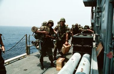 Marines of the 22nd Marine Expeditionary Unit (22nd MEU) aboard the amphibious assault ship USS SAIPAN (LHA 2) pick up their equipment before boarding a helicopter during Operation Sharp Edge. The Marines will be flown to the U.S. Embassy in Monrovia, Liberia, to augment security and evacuate U.S. and foreign nationals from the fighting between government and rebel forces