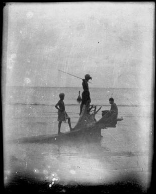 Three people sitting and standing on a beached tree stump,  Rabaul Harbour, New Guinea, ca. 1929 / Sarah Chinnery