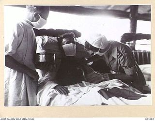 BOUGAINVILLE, 1945-06-18. PTE D. SMITHSON, 11 FIELD AMBULANCE (1), HAVING HIS WOUNDS DRESSED BY SISTER M.M. MCINNES (2) AT 109 CASUALTY CLEARING STATION. (A GENERAL VIEW OF THE SURGICAL WARD, 109 ..