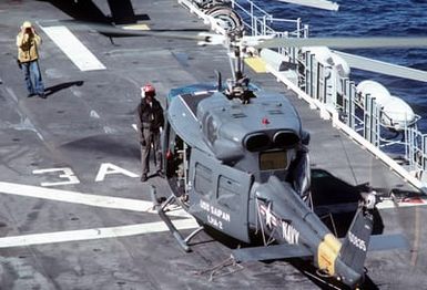 A flight deck crewman aboard the amphibious assault ship USS SAIPAN (LHA-2) prepares a UH-1N Iroquois helicopter for flight. The SAIPAN is taking part in exercise Ocean Venture '81