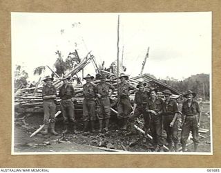 WAREO, NEW GUINEA. 1943-12. OFFICERS OF THE 2/23RD AUSTRALIAN INFANTRY BATTALION, GROUPED AROUND THE VICTORY FLAG. THIS FLAG WAS PREVIOUSLY RAISED OVER KOKODA, BUNA AND SATTELBERG. IDENTIFIED ..