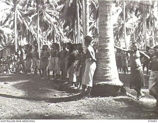 KARKAR ISLAND, NEW GUINEA. 1944-09-18. NATIVES RECRUITED FROM VILLAGES AWAITING ALLOTMENT BY PERSONNEL OF THE AUSTRALIAN NEW GUINEA ADMINISTRATIVE UNIT TO PLANTATIONS