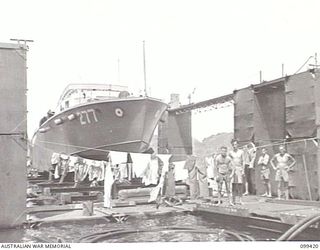 RABAUL, NEW BRITAIN, 1945-12-13. THE END SECTION OF AN AUSTRALIAN MADE FLOATING DOCK IN SIMPSON HARBOUR WITH A ROYAL NEW ZEALAND AIR FORCE CRASH BOAT IN THE SLIPS