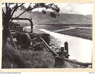 NADZAB, NEW GUINEA. 1945-09-14. A MOBILE PUMP IN USE AT 8 INDEPENDENT FARM PLATOON. IT IS DESIGNED FOR RIVERS SUBJECT TO RAPID FLOODING AND CHANGING OF COURSE. IT IS A CONVERSION OF AN OLD ..