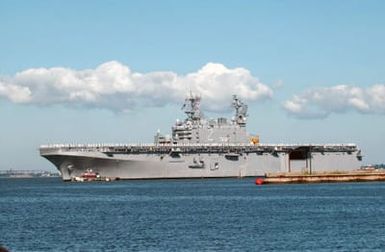 Starboard view of the US Navy (USN) Tarawa Class Amphibious Assault Ship USS SAIPAN (LHA 2) guided to the pier by tugboats as her Sailors man the rails. The SAIPAN returned to Naval Station (NS) Norfolk after completing a three-month surge deployment in support of the Global War on Terrorism (GWOT)