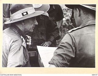 SUAIN PLANTATION, NEW GUINEA. 1944-12-10. MAJOR-GENERAL J.E.S. STEVENS, GENERAL OFFICER COMMANDING 6 DIVISION, (1), EXAMINING PATROL REPORTS, AND IN CONFERENCE WITH SENIOR OFFICERS