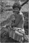 Young woman in short fiber skirt, holding infant