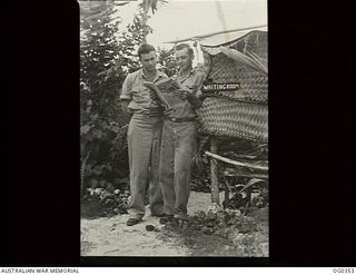 NEW GUINEA. C. 1944-05. TWO AIRMEN READING A PAPER IN THE OUTSIDE WAITING ROOM AWAITING DENTAL TREATMENT AT A RAAF DENTAL SECTION