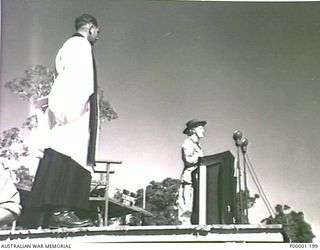 THE SOLOMON ISLANDS, 1945-08. BRITISH ENTERTAINER GRACIE FIELDS READING A LESSON DURING AN AUSTRALIAN THANKSGIVING SERVICE ON BOUGAINVILLE ISLAND. (RNZAF OFFICIAL PHOTOGRAPH.)