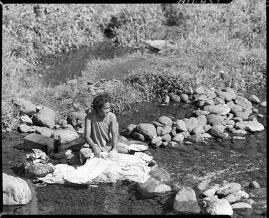 Unidentified woman washing clothes in a stream in Samoa