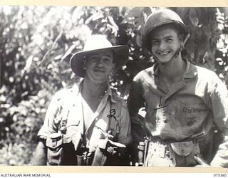 LAE, NEW GUINEA. 1944-02-18. NX122585 WARRANT OFFICER A. HOLLIER, HEADQUARTERS, NEW GUINEA FORCE (2) AND TECHNICAL SERGEANT DEATON, UNITED STATES ARMY (1) POSE FOR THEIR PHOTOGRAPH SHOWING THE ..