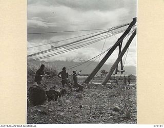 EVAPIA RIVER, NEW GUINEA, 1944-03-15. THE HUGE MAIN SUPPORT FROM THE SUSPENSION BRIDGE UNDER CONSTRUCTION OVER THE EVAPIA RIVER NEAR KESAWAI, BEING HOISTED INTO POSITION BY ENGINEERS FROM THE 2/4TH ..