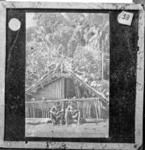 "Ugi" Two men outside house festooned with skulls