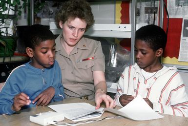 Adrian Hunter, left, and Joseph Arnold review the script for a mock shuttle launch with CHIEF Yeoman Lynda Blackwood as part of the Young Astronauts Program (YAP) at Chesterfield Heights Elementary School, Norfolk. CHIEF Fire Controlman (SW) Michael S. Stanton began the Chesterfield Heights chapter of YAP, an international educational program for pre-school, elementary and junior high school students promoting the study of science, mathematics and space-related subjects