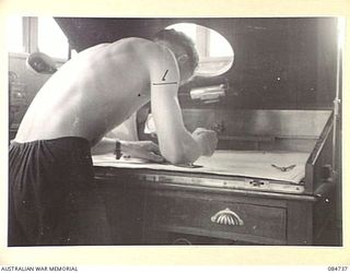 MADANG, NEW GUINEA. 1944-11-06. SUB- LIEUTENANT J K SULLIVAN, GUNNERY OFFICER ABOARD HMAS STAWELL, WORKING AT THE CHART TABLE ON THE BRIDGE