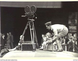 SYDNEY, AUSTRALIA. 1942-12-12. FROM THE TOP OF A CINEPHOTOGRAPHERS VEHICLE TWO TINY TOTS GET A GOOD VIEW OF THE DISPLAY OF AUSTRALIAN-MADE MUNITIONS IN A PROCESSION THROUGH THE STREETS OF SYDNEY. ..