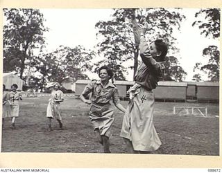 INDOOROOPILLY, BRISBANE, QUEENSLAND. 1945-02-19. SIGNALWOMAN J. BALLARD THROWING FOR GOAL IN RECREATIONAL BASKETBALL TRAINING DURING THE VISIT OF COLONEL S.H. IRVING, CONTROLLER AUSTRALIAN WOMEN'S ..
