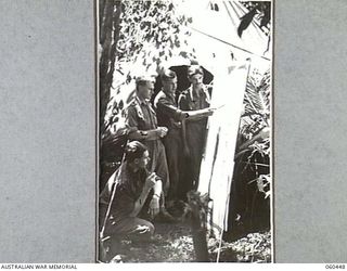 FINSCHHAFEN AREA, NEW GUINEA. 1943-11-07. STAFF OFFICERS OF HEADQUARTERS, ROYAL AUSTRALIAN ARTILLERY, 9TH AUSTRALIAN DIVISION, STUDYING THE TACTICAL POSITION ON A MAP OUTSIDE HEADQUARTERS. THEY ..