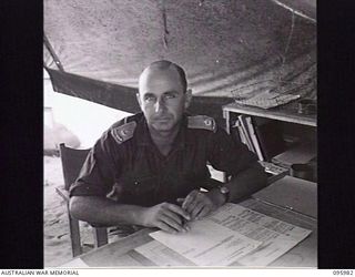 CAPE WOM, WEWAK AREA, NEW GUINEA. 1945-09-01. MAJOR E.S. OWENS, HEADQUARTERS 6 DIVISION AT HIS DESK