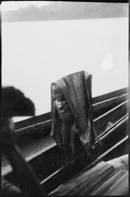 Person in a canoe sheltering under a bark rain hood, Ramu River, New Guinea, 1935 / Sarah Chinnery