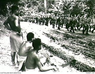 THE SOLOMON ISLANDS, 1945-09-19. BOUGAINVILLE ISLAND NATIVES WATCH AS JAPANESE TROOPS FROM NAURU ISLAND MARCH BY ON THEIR WAY FROM TOROKINA TO AN INTERNMENT CAMP. (RNZAF OFFICIAL PHOTOGRAPH.)