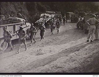 Troops of the 2/12th Battalion passing vehicles held up at the Rouna Traffic Control Post No. 2 because of blasting further along the road. Shown: TX5149 Private (Pte) G T Moore (1); QX3715 Lance ..