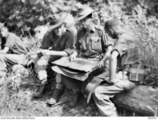 WEWAK AREA, NEW GUINEA, 1945-07-03. PERSONNEL OF 2/6 SURVEY BATTERY, ROYAL AUSTRALIAN ARTILLERY, DISCUSSING THE SURVEY PLAN TO PROVIDE ACCURATE POSITIONS AND INFORMATION TO THE 25-POUNDER FIELD ..