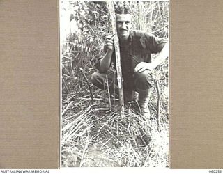 FARIA RIVER AREA, NEW GUINEA. 1943-11-07. NX98025 PRIVATE T. CHIPLIN OF KENSINGTON, NSW, AND OF THE 2/27TH AUSTRALIAN INFANTRY BATTALION MARKING THE GRAVE OF AN UNKNOWN JAPANESE SOLDIER