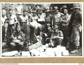 RAMU VALLEY, NEW GUINEA. 1943-12-22. PERSONNEL OF THE 2/31ST AUSTRALIAN INFANTRY BATTALION GATHER AROUND WHILE THE CHRISTMAS MAIL IS BEING SORTED