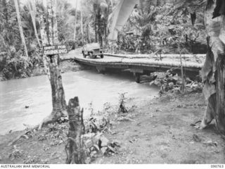 MILNE BAY, NEW GUINEA. 1942-08-24. A BRIDGE CONSTRUCTED FROM COCONUT LOGS SAGGING DUE TO FLOODWATERS WHICH HAD PREVIOUSLY COVERED IT