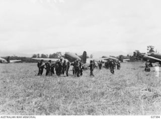 WANIGELA, NEW GUINEA. 1942-10. MEMBERS OF THE 3RD BATTALION, 128TH REGIMENT 32ND U.S. DIVISION AND 2/6TH AUSTRALIAN INDEPENDENT COMPANY ALIGHTING FROM TRANSPORT PLANES AFTER BEING FLOWN IN FROM ..