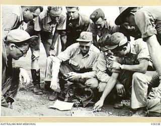 NEW GUINEA, 1942-08-10. A CLOSE-UP OF AMERICAN AND AUSTRALIAN BOMBER CREWS GROUPED AROUND THEIR TARGET MAPS, AS THEY GET INSTRUCTIONS BEFORE SETTING OUT ON A RAID OVER JAP BASES