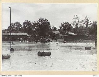 LAE, NEW GUINEA. 1945-10-14. A TRUCK AT 2/11 MOBILE LAUNDRY, FIRST ARMY, TRAPPED BY FLOOD WATERS. FOLLOWING HEAVY RAINS THE BUTIBUM RIVER OVERFLOWED ITS BANKS, FLOODED THE ROAD AND ADJOINING UNITS, ..