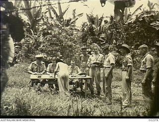 TOROKINA, BOUGAINVILLE ISLAND, SOLOMON ISLANDS. C. 1945-02-23. FINANCE OFFICER AND RAAF PAYMASTER PERFORMS HIS DUTY AMID THE TROPICAL JUNGLE ON BOUGAINVILLE ISLAND, FAR FROM THE COMFORTS OF A ..