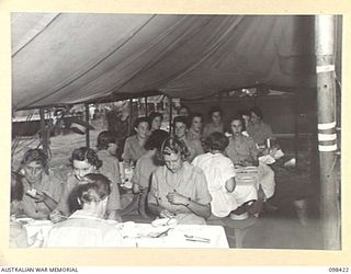 RABAUL, NEW BRITAIN. 1945-10-31. AUSTRALIAN ARMY MEDICAL WOMEN'S SERVICE PERSONNEL OF 118 GENERAL HOSPITAL HAVING THEIR MID-DAY MEAL IN THEIR MAKE SHIFT MESS - TEMPORARILY ERECTED TENT ..