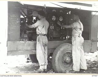 LAE BASE AREA, NEW GUINEA. 1944-12-04. NX29395 CORPORAL R.W. CUMMINS (1) AND NX29222 CRAFTSMAN E.E. ROBERTS (2) OF THE 2/77TH LIGHT AID DETACHMENT WORKING ON A 25KVA ELECTRICITY GENERATING SET