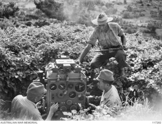 NAURU ISLAND. 1945-09-14. JAPANESE ARMY OFFICERS EXPLAINING THE DETAILS OF ONE OF THEIR RANGE FINDERS TO AN OFFICER OF THE 31/51ST INFANTRY BATTALION SOON AFTER THE UNIT HAD TAKEN OVER THE ISLAND