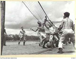 1943-04-12. NEW GUINEA. WITH THE PLAYERS IN ATTITUDES SUGGESTIVE OF BALLET DANCERS THE BALL DROPS TO THE GROUND DURING A GAME OF VOLLEYBALL IN NEW GUINEA BY AMERICAN AIR PILOTS AND CREWS. ..