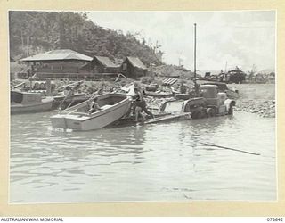 LAE, NEW GUINEA. 1944-05-28. A MOTOR LAUNCH BEING EASILY LAUNCHED BY MEMBERS OF THE 2ND MARINE FOOD SUPPLY PLATOON FROM A TANK TRAILER. THE TRAILER HAS BEEN REVERSED WELL INTO THE WATER DOWN A RAMP ..