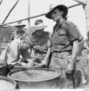 MUSCHU ISLAND, NEW GUINEA, 1945-09-08. THE JAPANESE OFFICER IN CHARGE, SIGNS THE RECEIPT FOR EQUIPMENT, UNDER SUPERVISION OF WARRANT OFFICER 2 A. KLESTADT. JAPANESE SOLDIERS ON THE ISLAND, UNDER ..