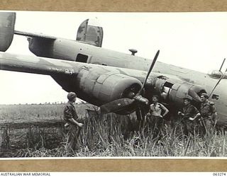 FAITA, NEW GUINEA. 1944-01-07. PERSONNEL OF THE 2/2ND COMMANDO SQUADRON LOOKING OVER AN AMERICAN LIBERATOR (B-24) WHICH CRASHED ON THE AIRSTRIP RETURNING FROM A RAID ON WEWAK. THEY ARE: TROOPER G. ..